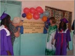 Visitors and graduates in gowns beside a balloon-decorated plaque for the Rosie-Dilys Administration Block