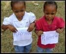 Two young girls in school uniform holding up handwritten name cards