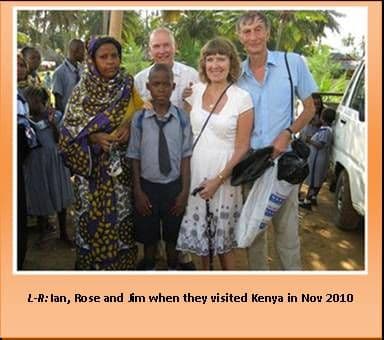 Three UK visitors standing with a Kenyan woman and schoolchildren outdoors