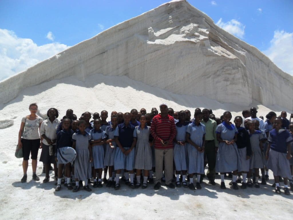 Pupils and teachers in uniform standing at the foot of a huge white mound of salt