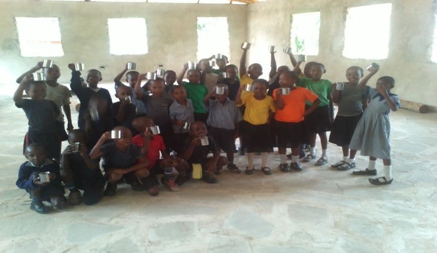 A large group of pupils cheering and raising their arms inside a hall