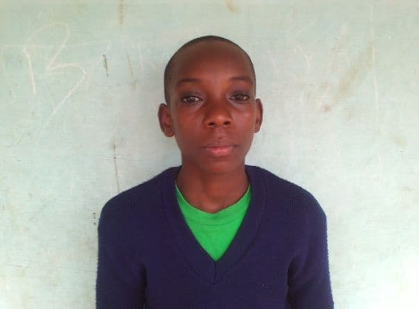 Head-and-shoulders portrait of a schoolboy in a navy jumper against a white wall