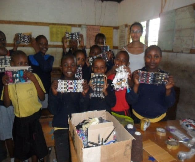 Pupils in a classroom holding up decorated bags and crafts they have made