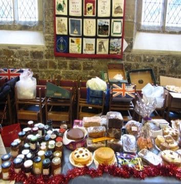 A table of jams, cakes and biscuits decorated with Union flags and tinsel