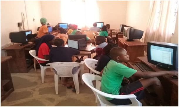 Pupils sitting at desktop computers around the walls of the school computer room