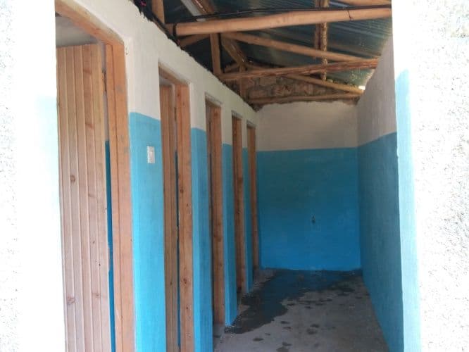Corridor inside the toilet block with blue-painted walls and wooden cubicle doors