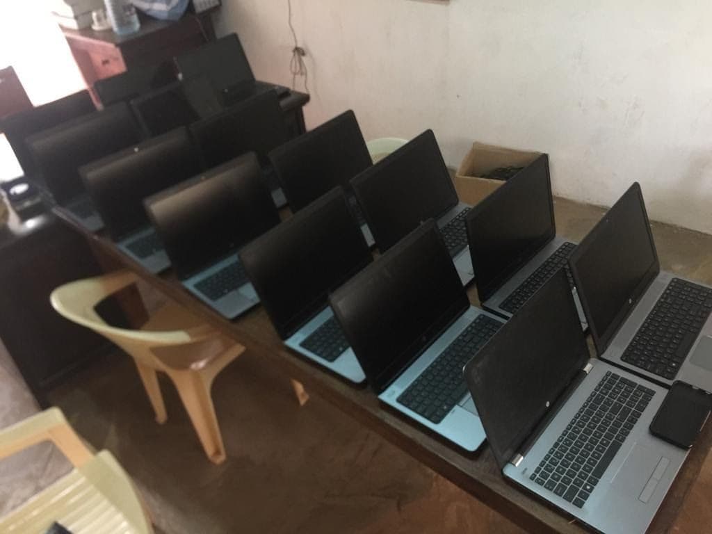 Rows of new open laptops lined up on a long table in a classroom