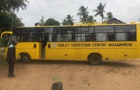 Yellow school bus marked Emley Education Centre Msambweni parked on a dirt yard