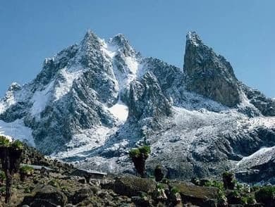 Jagged snow-covered mountain peaks under a blue sky