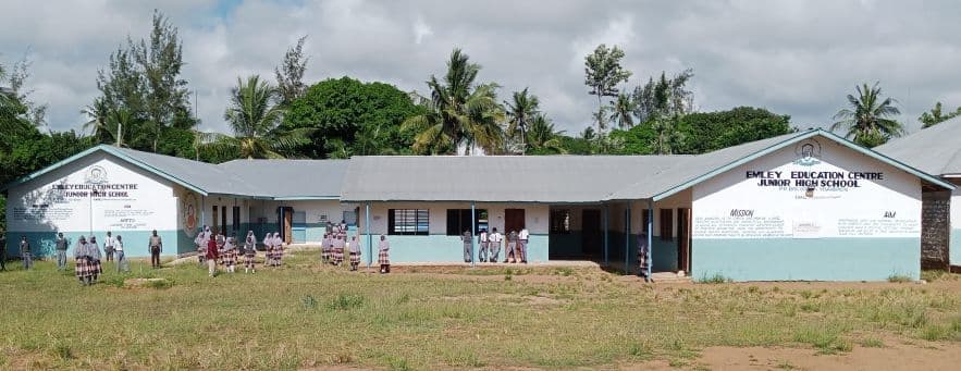 Single-storey Emley Education Centre Junior High School building with pupils on the grass in front