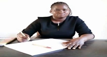 Woman in a black top writing on paper at a desk