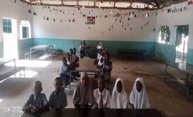 Pupils seated at long tables in the dining hall, decorated with bunting and a Kenyan flag