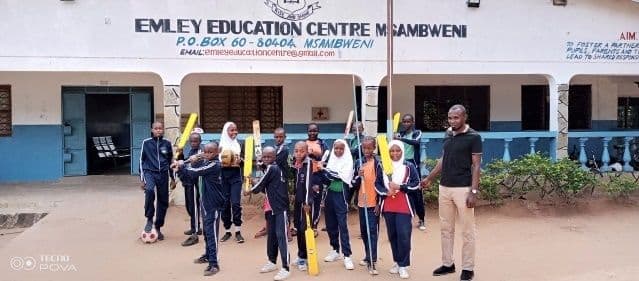 Pupils in tracksuits holding cricket bats with a teacher outside the Emley Education Centre building