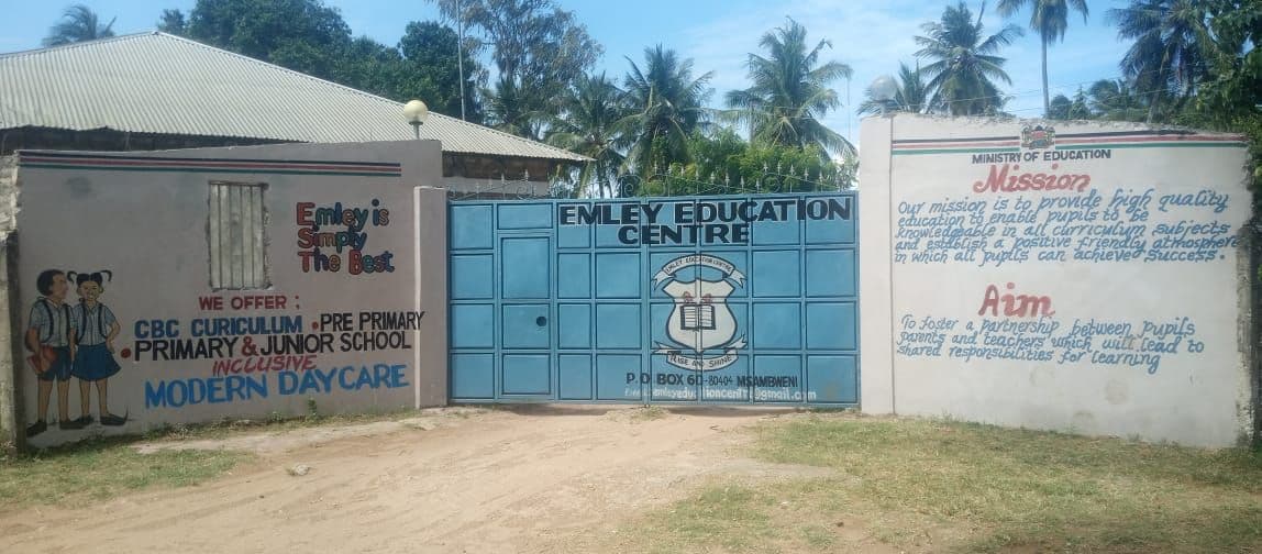 Emley Education Centre's blue front gate between painted walls showing the school's mission, aim and offer