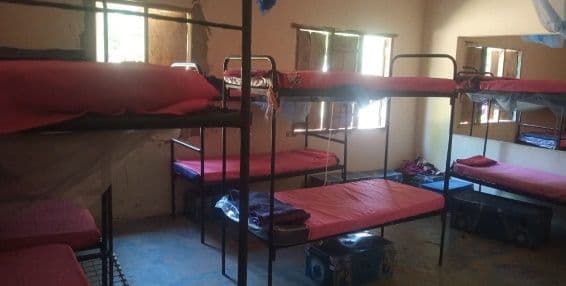 Dormitory with metal bunk beds made up with red mattresses and blankets