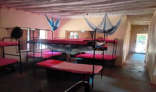 Boarding dormitory with bunk beds, red mattresses and mosquito nets