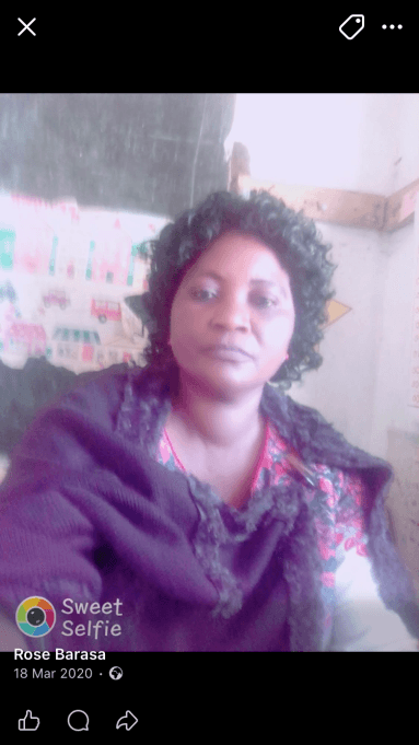 Phone screenshot of a selfie of a woman in a purple top in a classroom