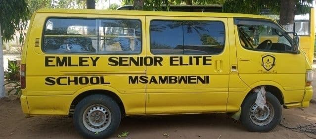 Yellow school van marked Emley Senior Elite School Msambweni, parked under trees