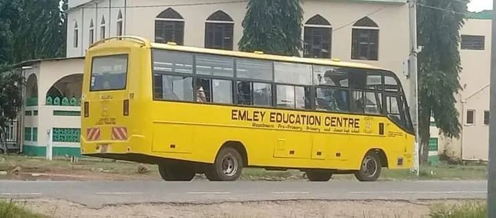 Yellow Emley Education Centre school bus parked on a roadside in front of a building