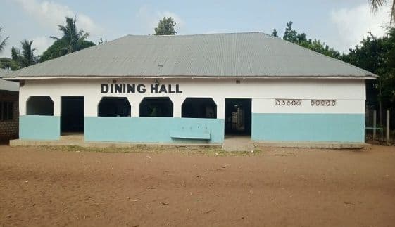 Exterior of the white and blue school dining hall building with an iron roof