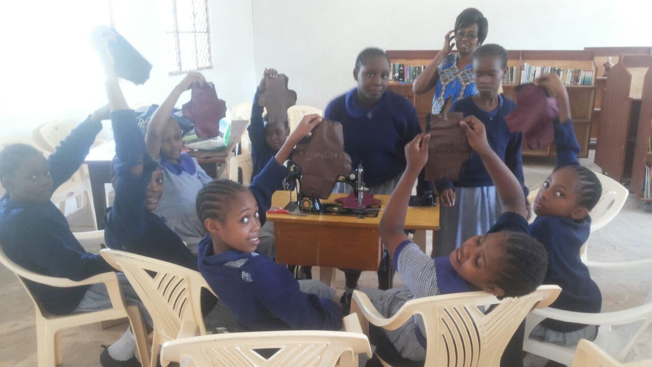 Schoolgirls in a classroom holding up finished washable sanitary shields