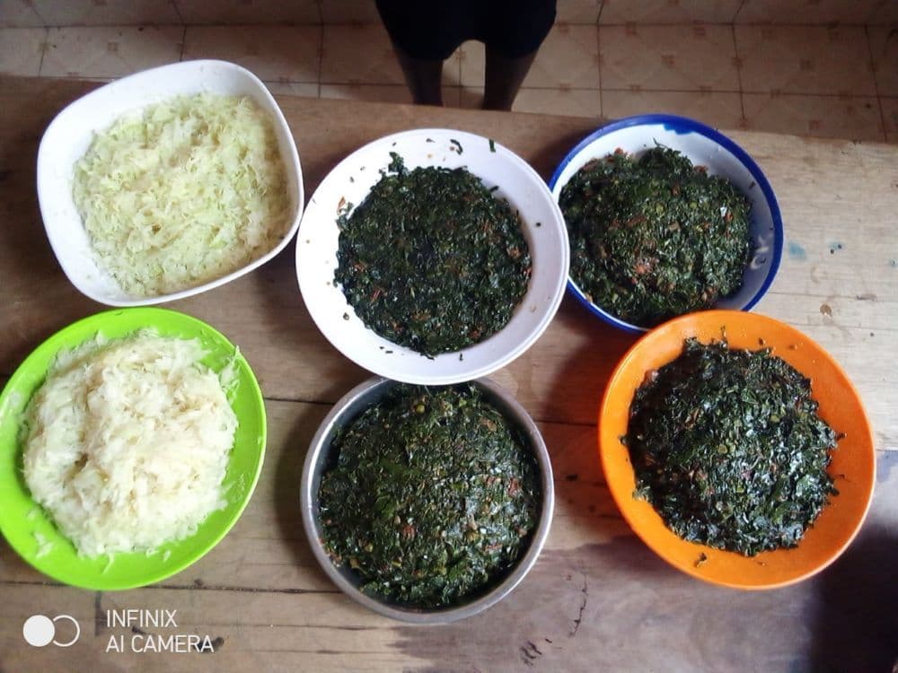 Six bowls of shredded cabbage and cooked green vegetables on a table