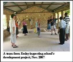 Visitors walking around an unfinished building with stone walls and a roof on timber trusses