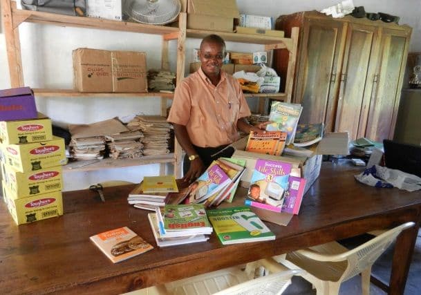 The head teacher at his desk stacked with new textbooks and exercise books in the school office