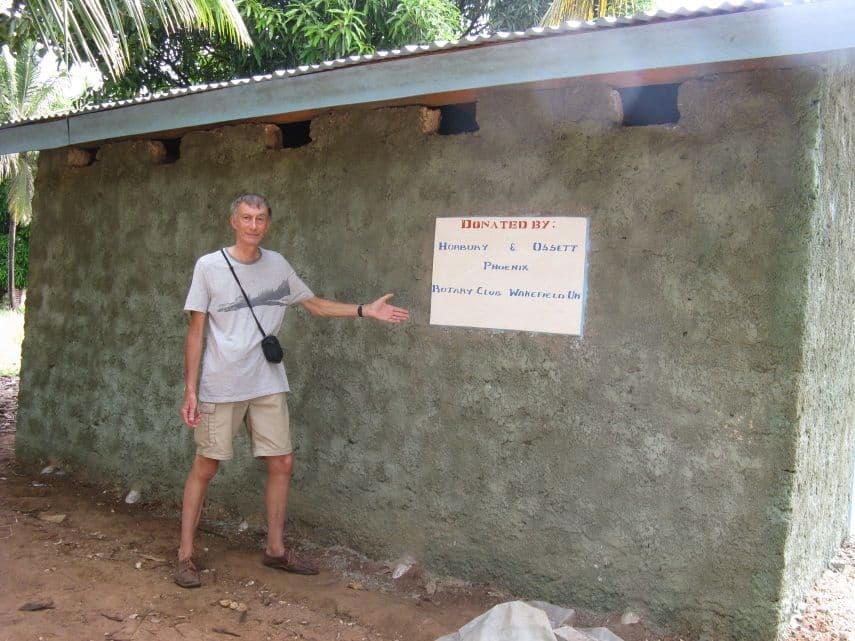 A visitor pointing to a sign on the wall of a newly built block of school toilets