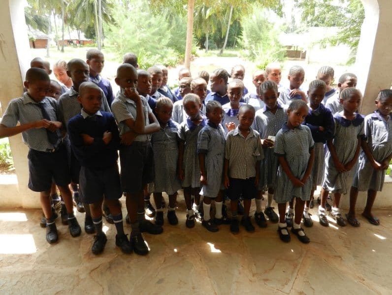 A large group of sponsored pupils in school uniform standing together on a veranda