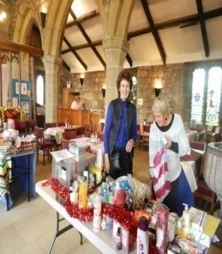 Two women at a tombola table of toiletries and prizes