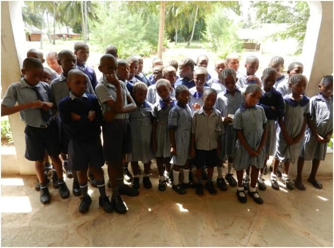 A large group of sponsored pupils in school uniform standing together on a veranda