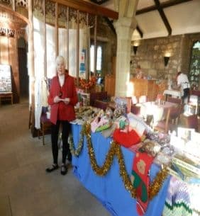 A woman beside a table of Christmas gifts decorated with tinsel