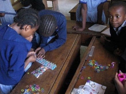 Pupils at their desks making bracelets from coloured rubber bands