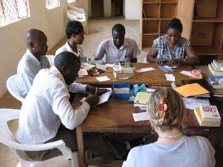 Teachers seated round a library table writing up and cataloguing books