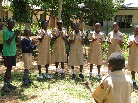 Scouts in khaki uniform singing outdoors in a semicircle