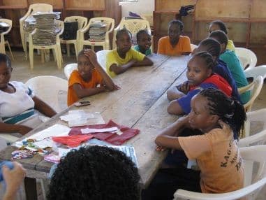 Girls seated around a library table sorting pieces of fabric