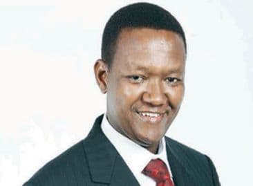 Smiling man in a dark pinstripe suit and red tie
