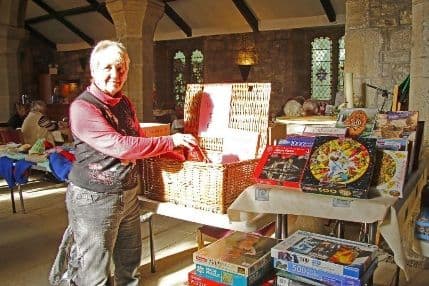 Woman opening a wicker hamper beside a table of jigsaw puzzles