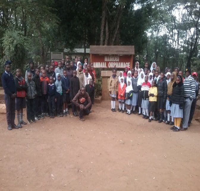 Pupils and teachers lined up in front of an animal orphanage entrance sign