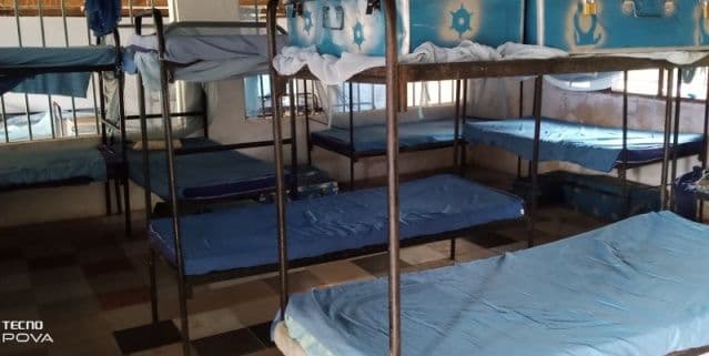 Boarding dormitory with rows of metal bunk beds and blue mattresses