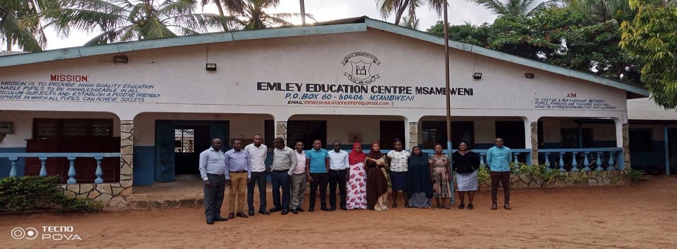 Teaching staff standing in a line in front of the Emley Education Centre Msambweni building