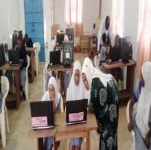 Pupils in white headscarves working at laptops in the school computer lab