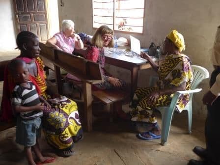 Women and children wait on benches as volunteers check eyes at a table in a small room