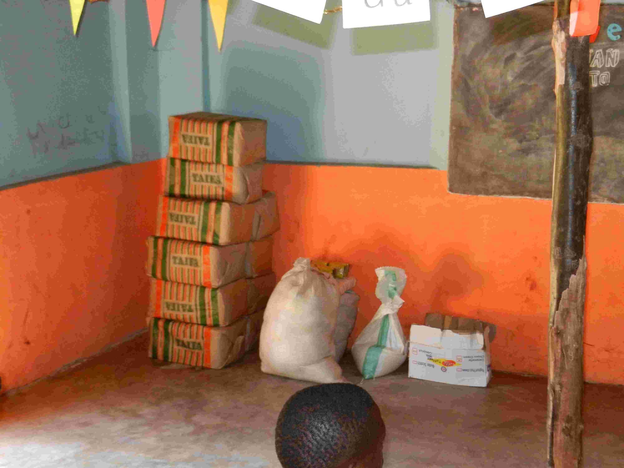 Boxes of cooking fat and sacks of flour stacked in a classroom corner