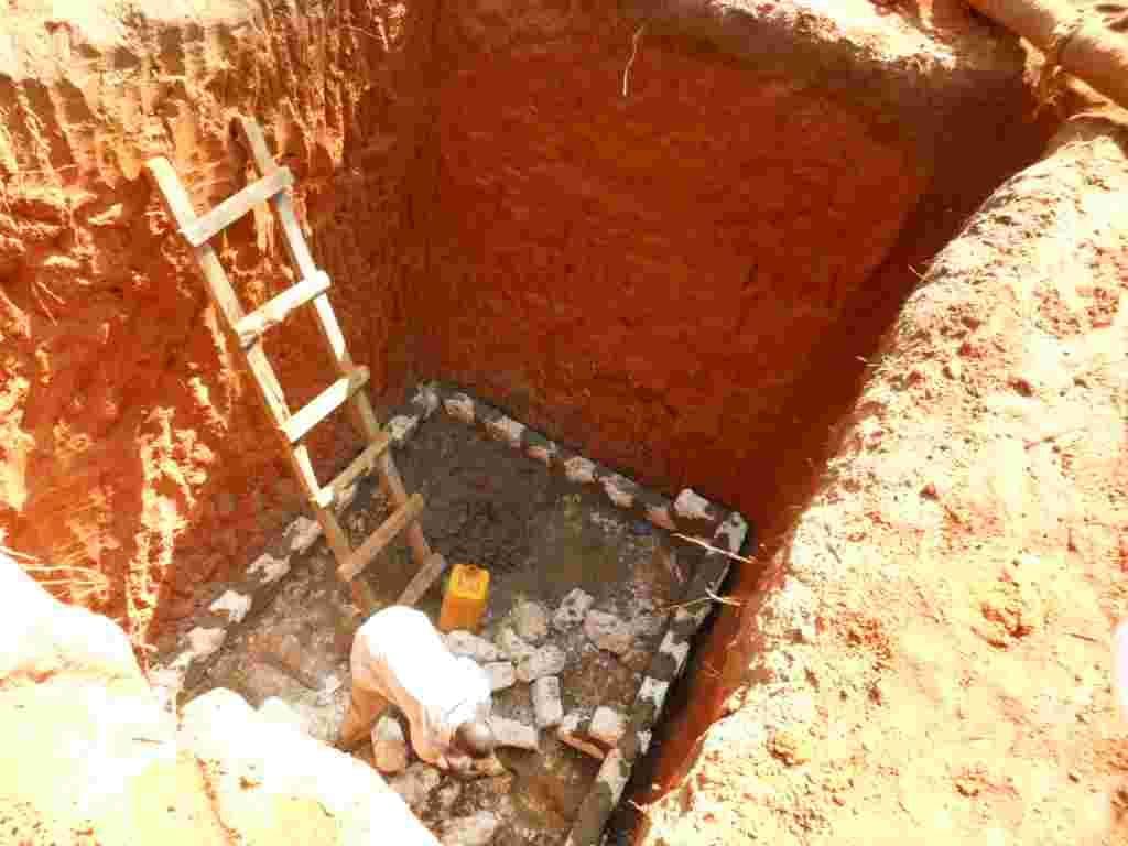 A deep pit dug for a septic tank with a ladder and block base