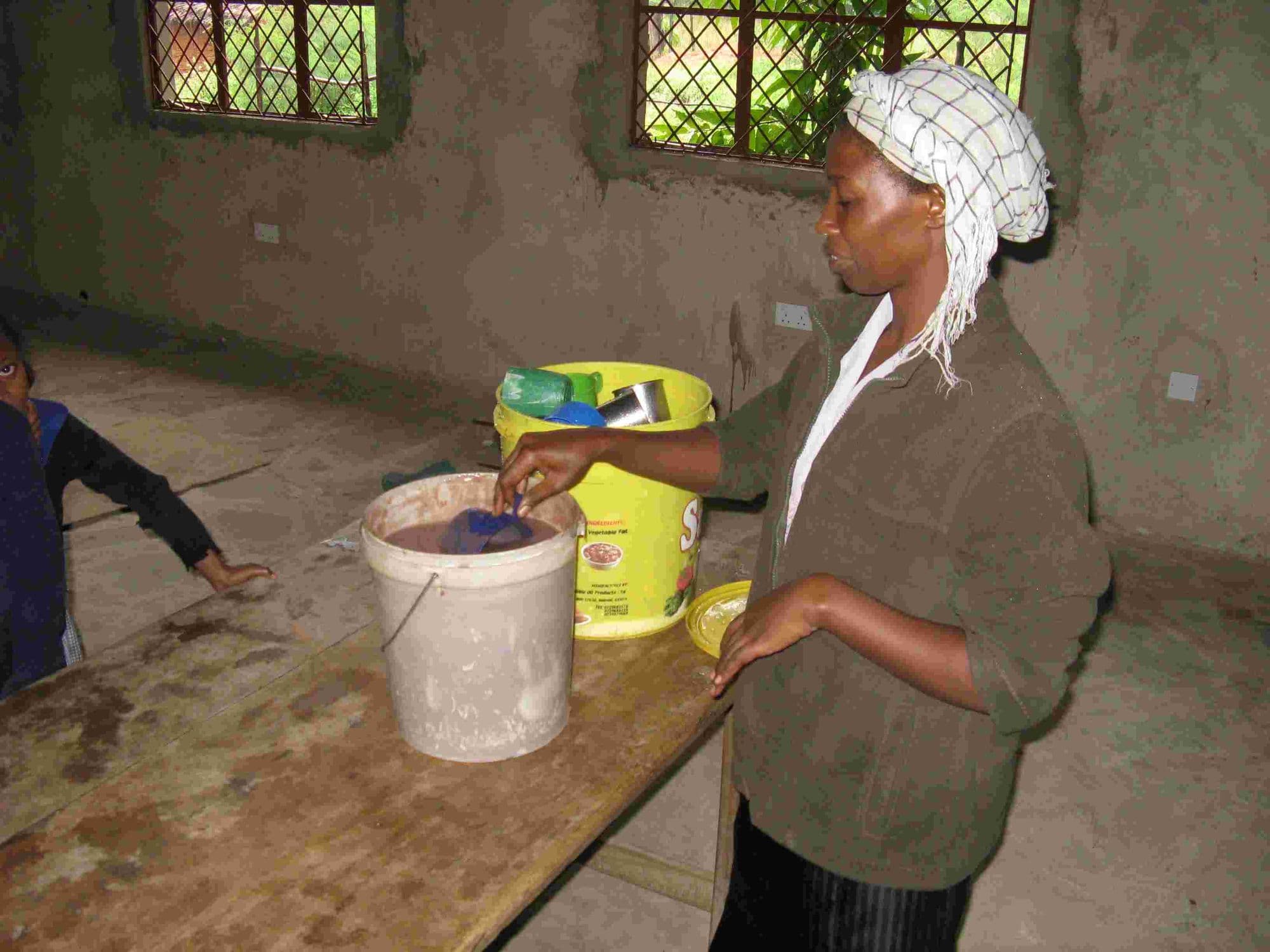 A cook stirring porridge in a bucket for the breakfast club