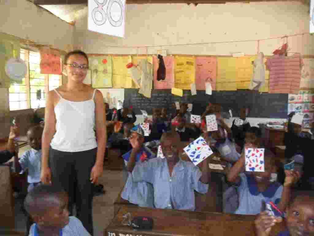 A student teacher standing in a classroom while pupils hold up their craft cards
