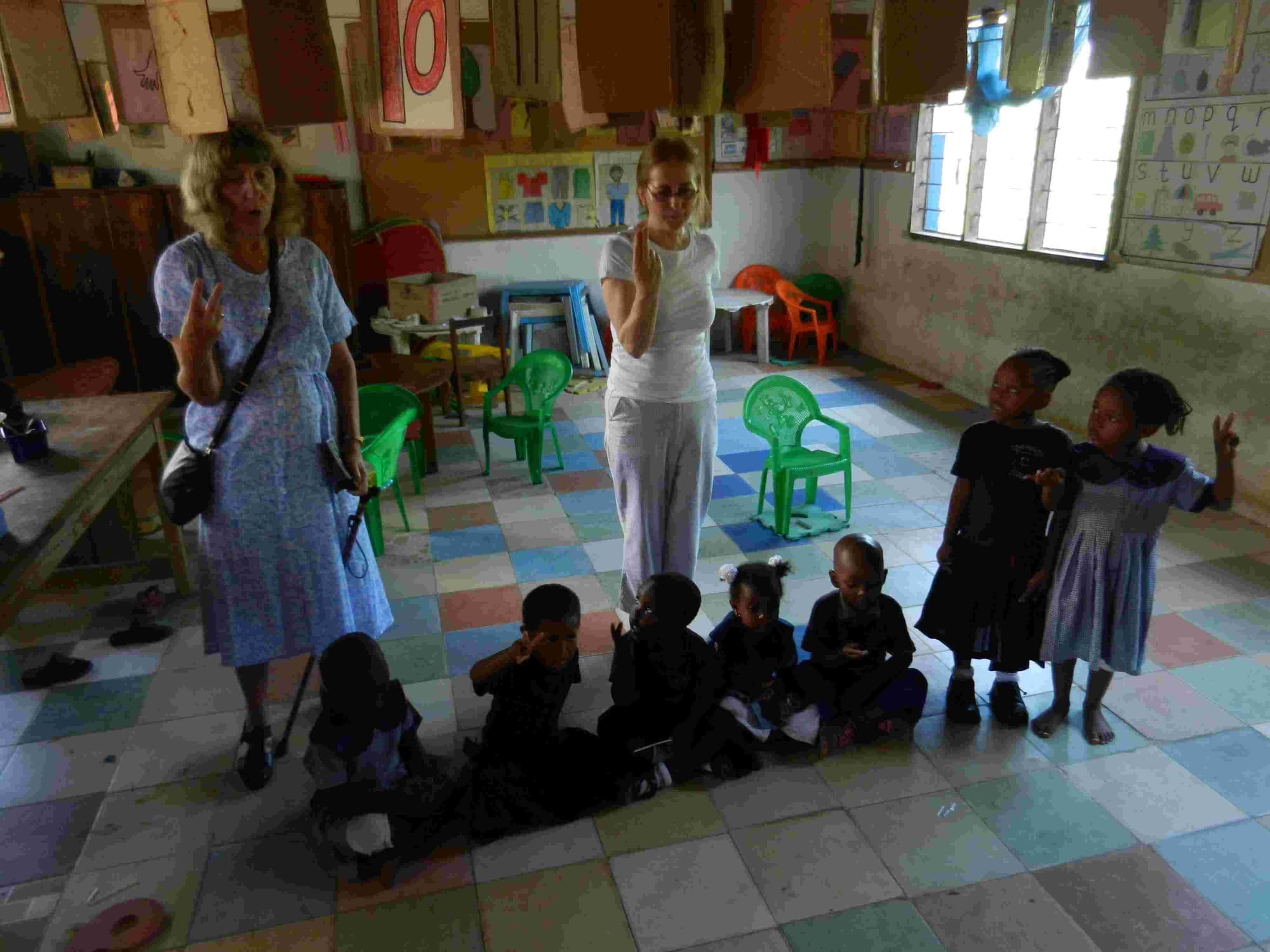 Visitors leading young pupils in a game on a colourful tiled classroom floor