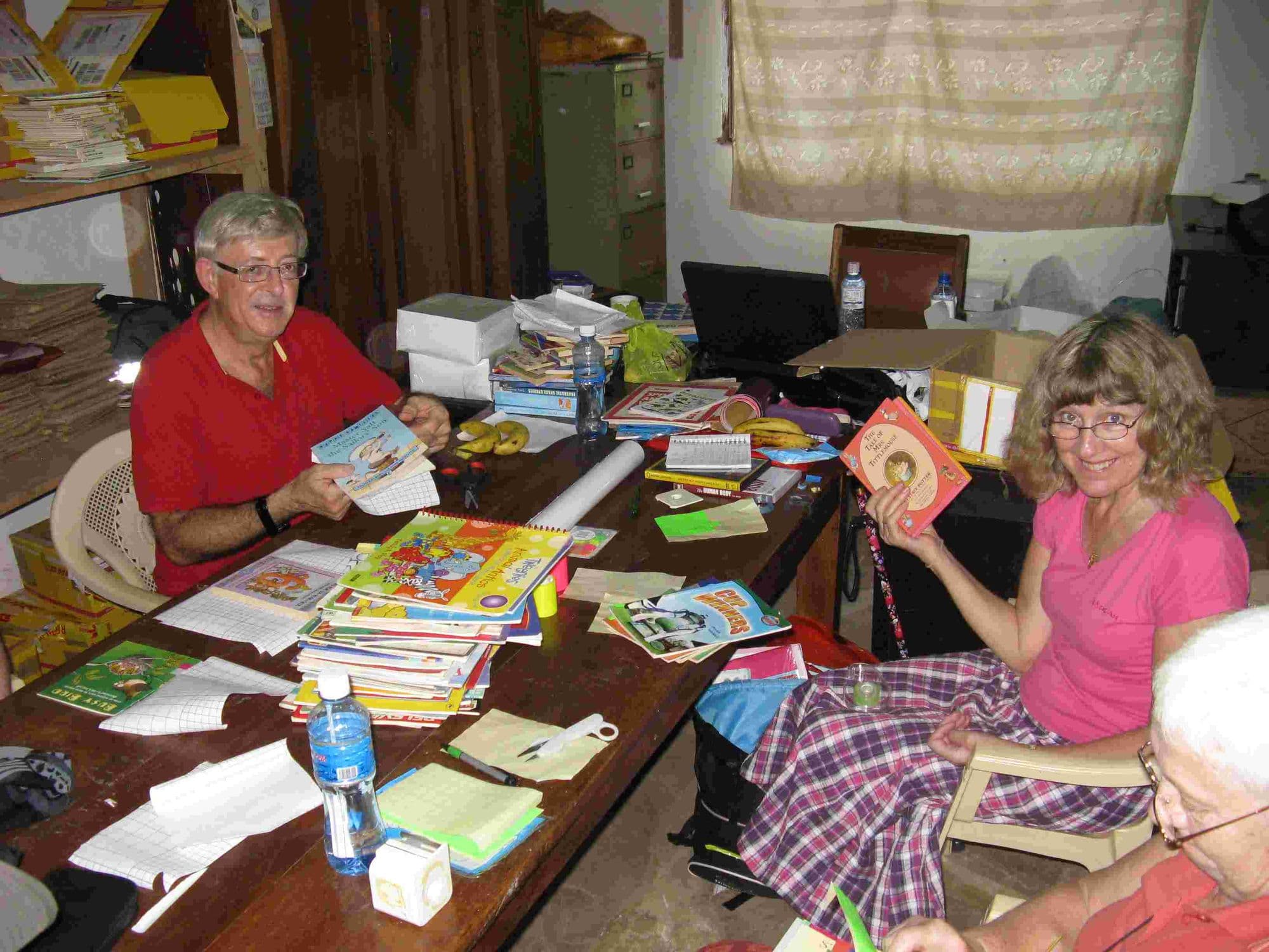 Visitors seated at tables covered with children's books, covering them for the library